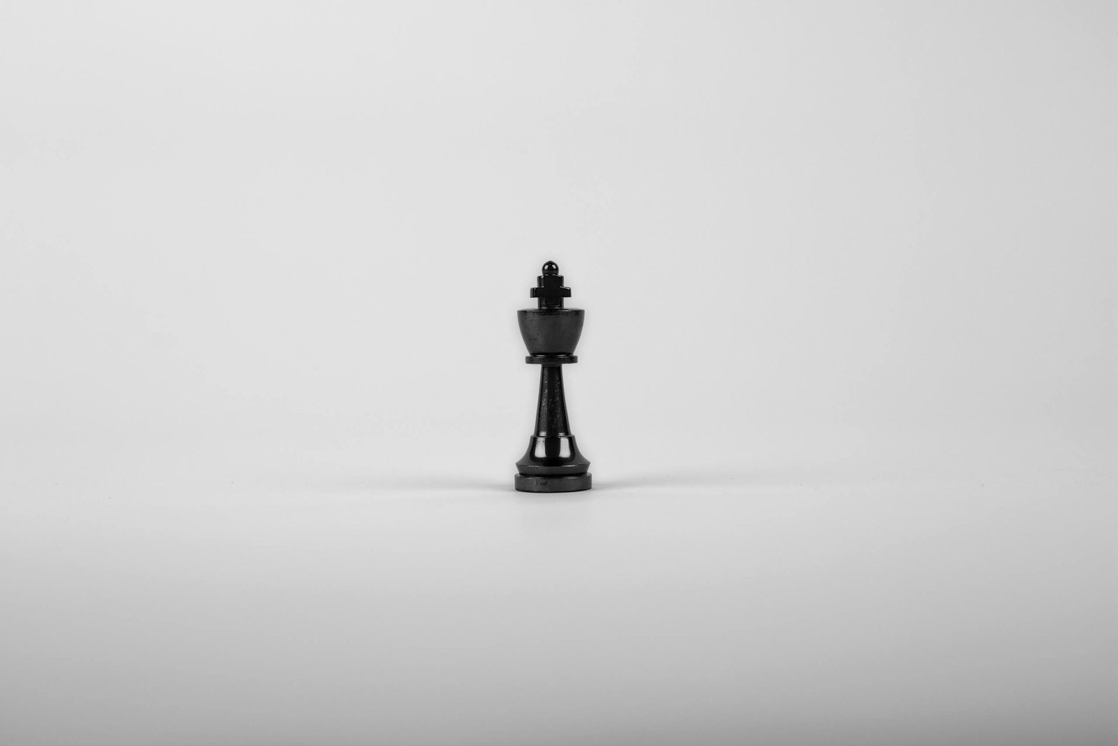 A minimalist black chess king piece on a white background, representing strategy and power.